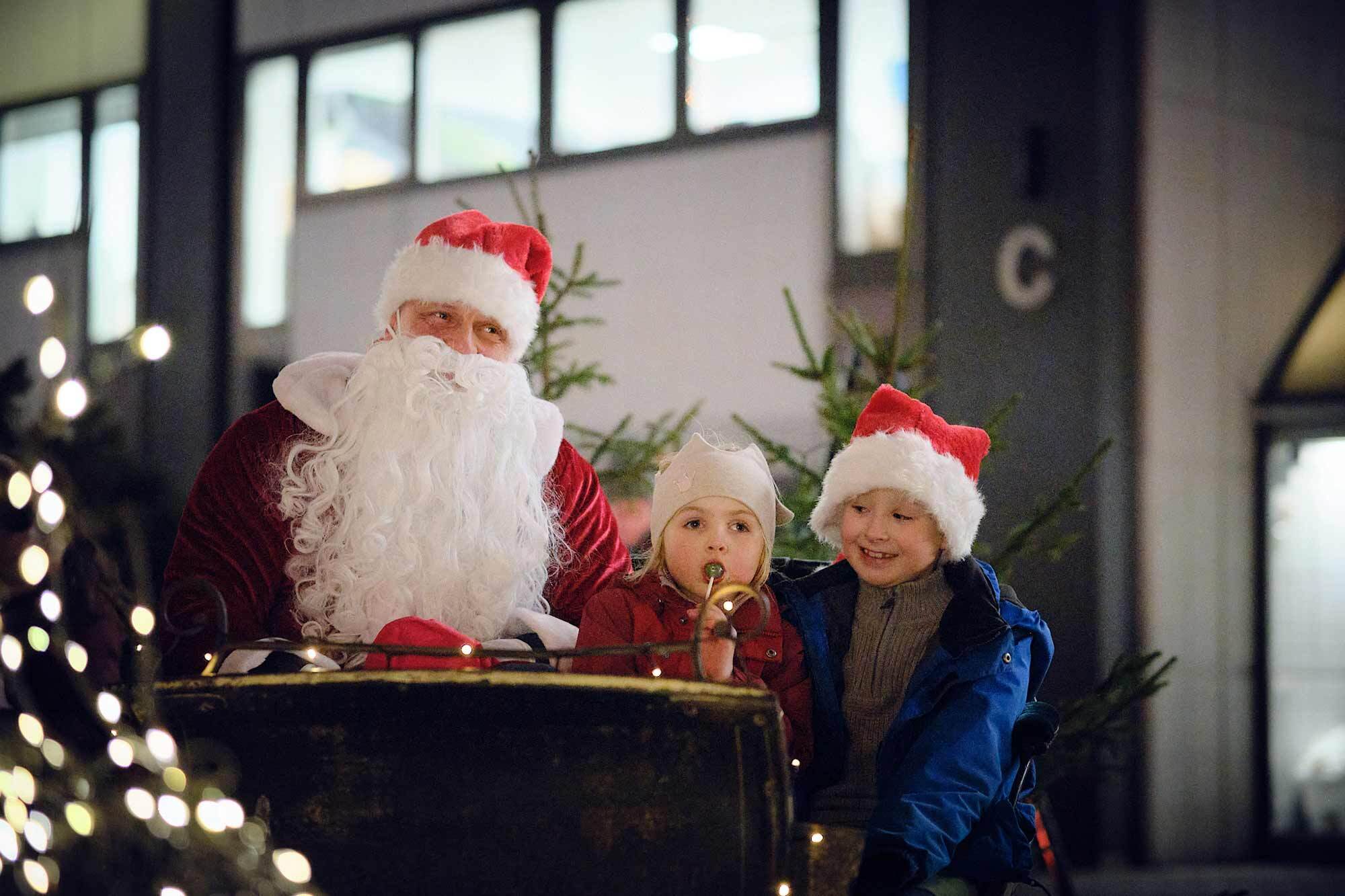 Julenissen i slede med to barn ved siden av seg